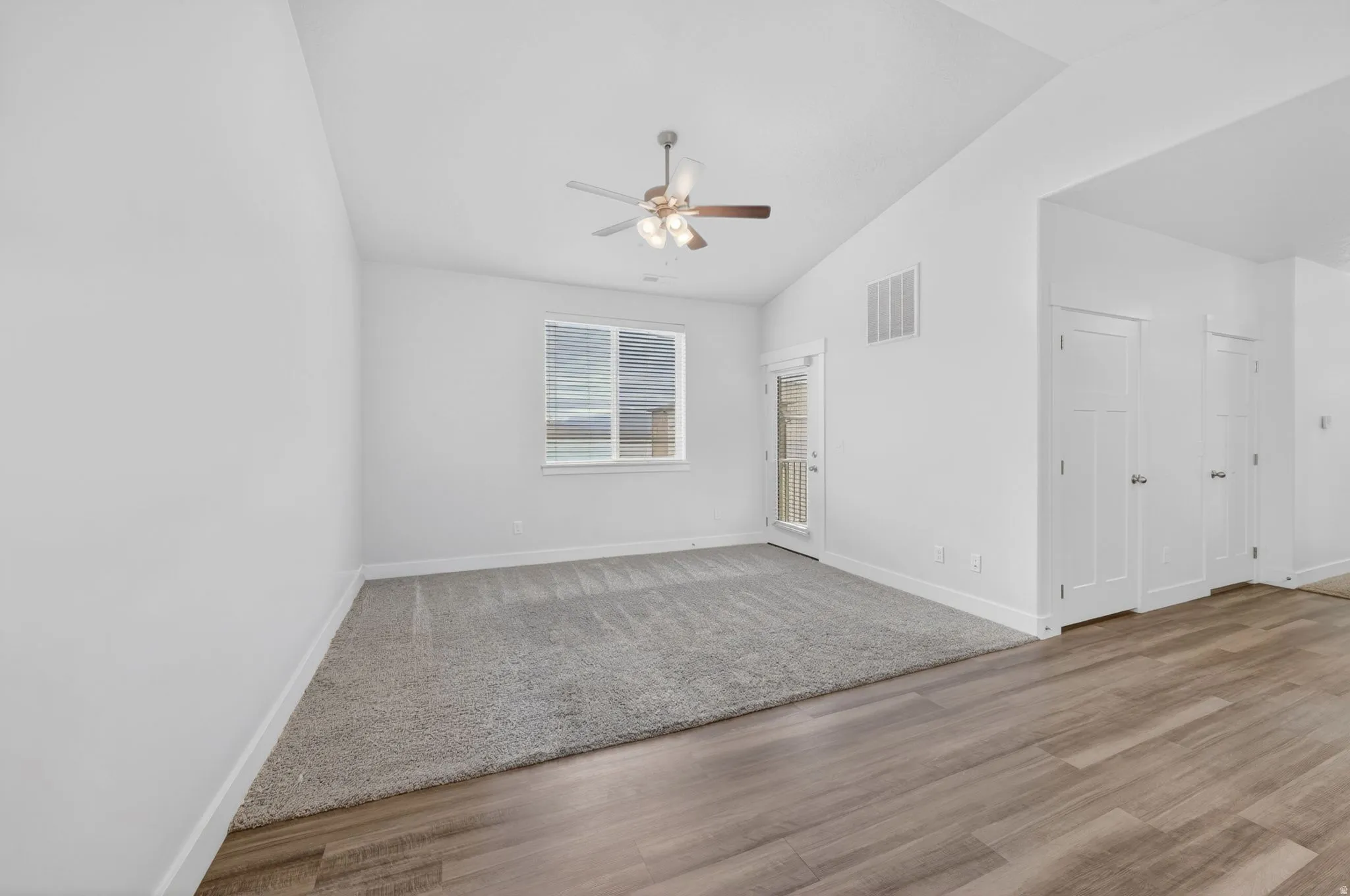 Unfurnished room featuring a ceiling fan, light wood finished floors, and vaulted ceiling