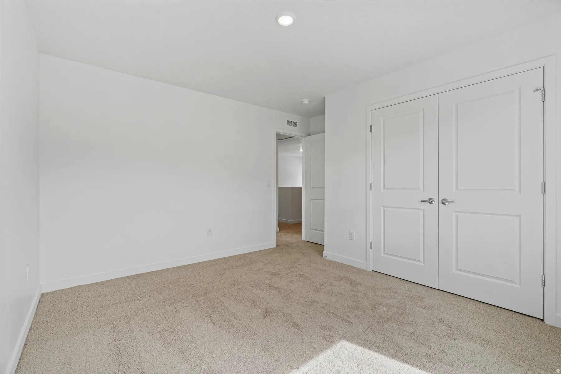 Neutral color palette, plush carpeting, recessed ceiling lighting, and panel doors with satin nickel hardware