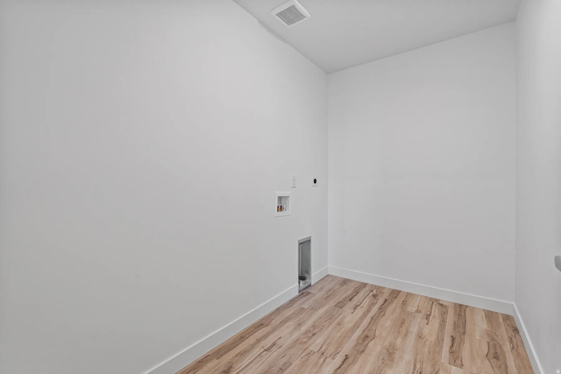 Utility space featuring light wood-finish flooring, white baseboards, and a white ceiling with a central vent