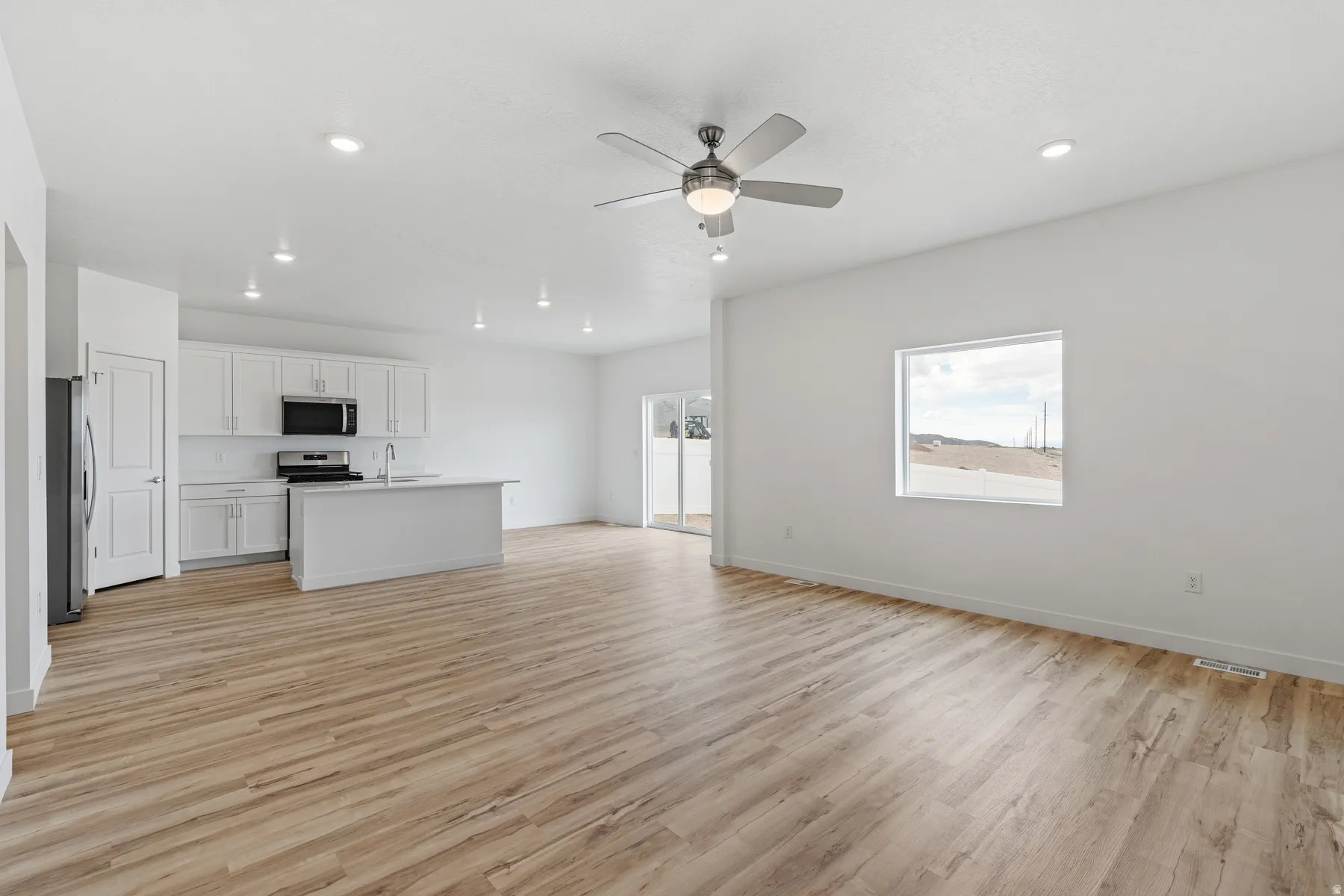 Open-concept living area featuring wood-finish flooring, recessed lighting, and a ceiling fan