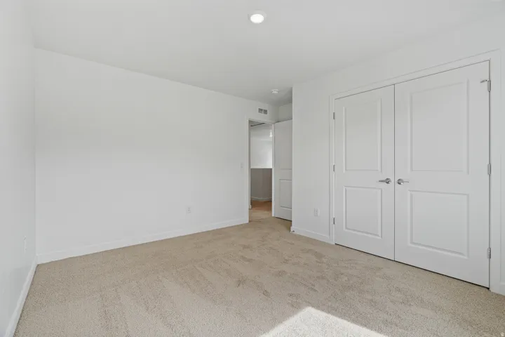 Neutral color palette, plush carpeting, recessed ceiling lighting, and panel doors with satin nickel hardware