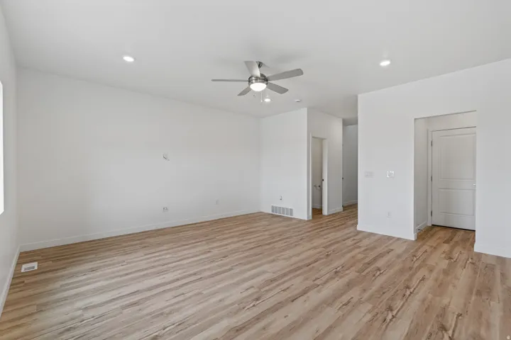 Spacious room featuring wood-finish flooring, recessed lighting, a ceiling fan with integrated light, white baseboards, and white painted walls