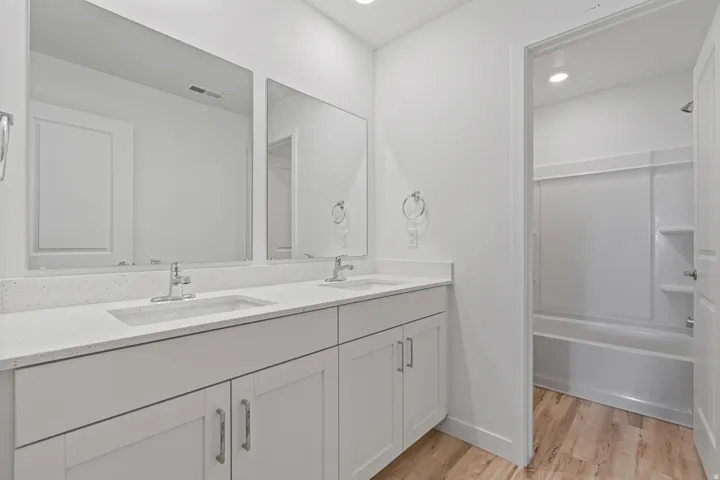 White vanity with dual integrated sinks, light-toned countertop, and two mirrors
