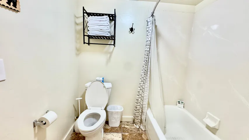 Full bath with shower / bathtub combination with curtain and stone finish floors