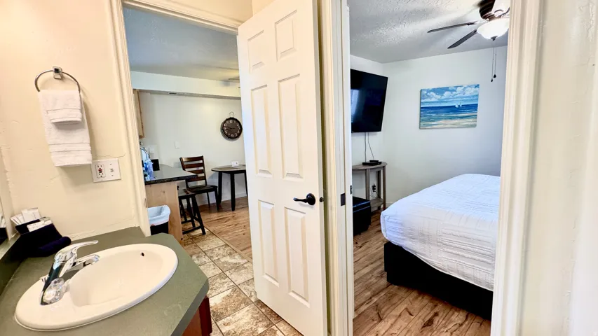 Bathroom featuring a textured ceiling, a ceiling fan, connected bathroom, vanity, and light wood-style flooring
