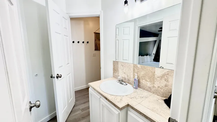 Bathroom featuring vanity, backsplash, and dark wood-style flooring
