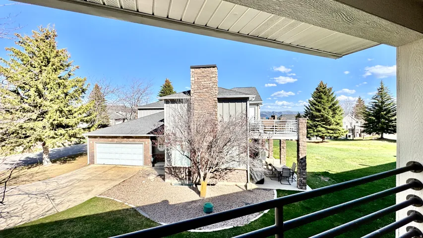 View of side of property with an attached garage, a balcony, concrete driveway, board and batten siding, and a yard