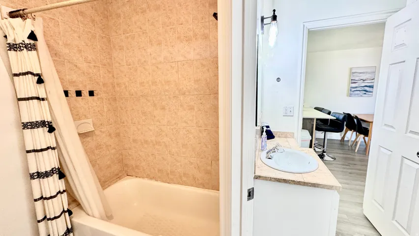 Bathroom with shower / bath combo, vanity, and light wood-style floors