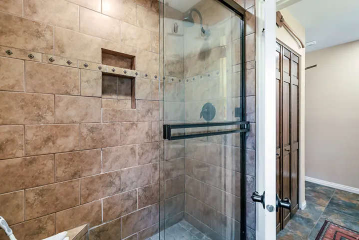 Bathroom featuring a shower stall and stone finish floors
