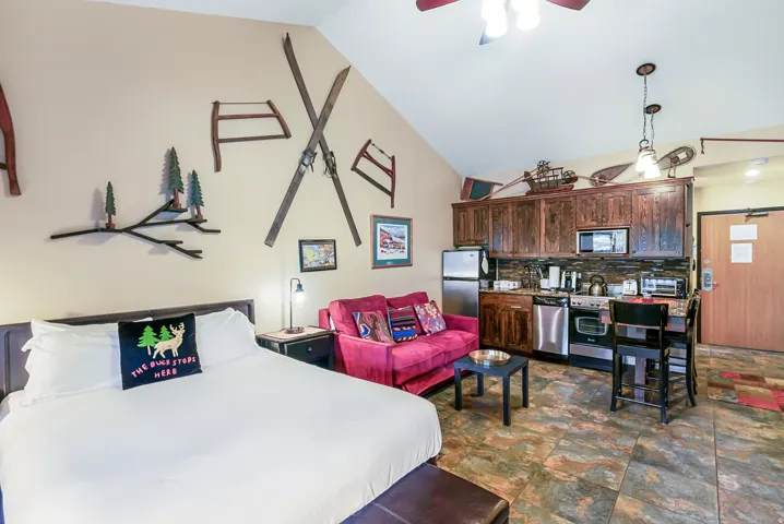 Bedroom with vaulted ceiling, stone finish flooring, a ceiling fan, and freestanding refrigerator