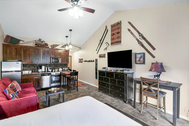 Living room with vaulted ceiling, a ceiling fan, and dark tile patterned floors