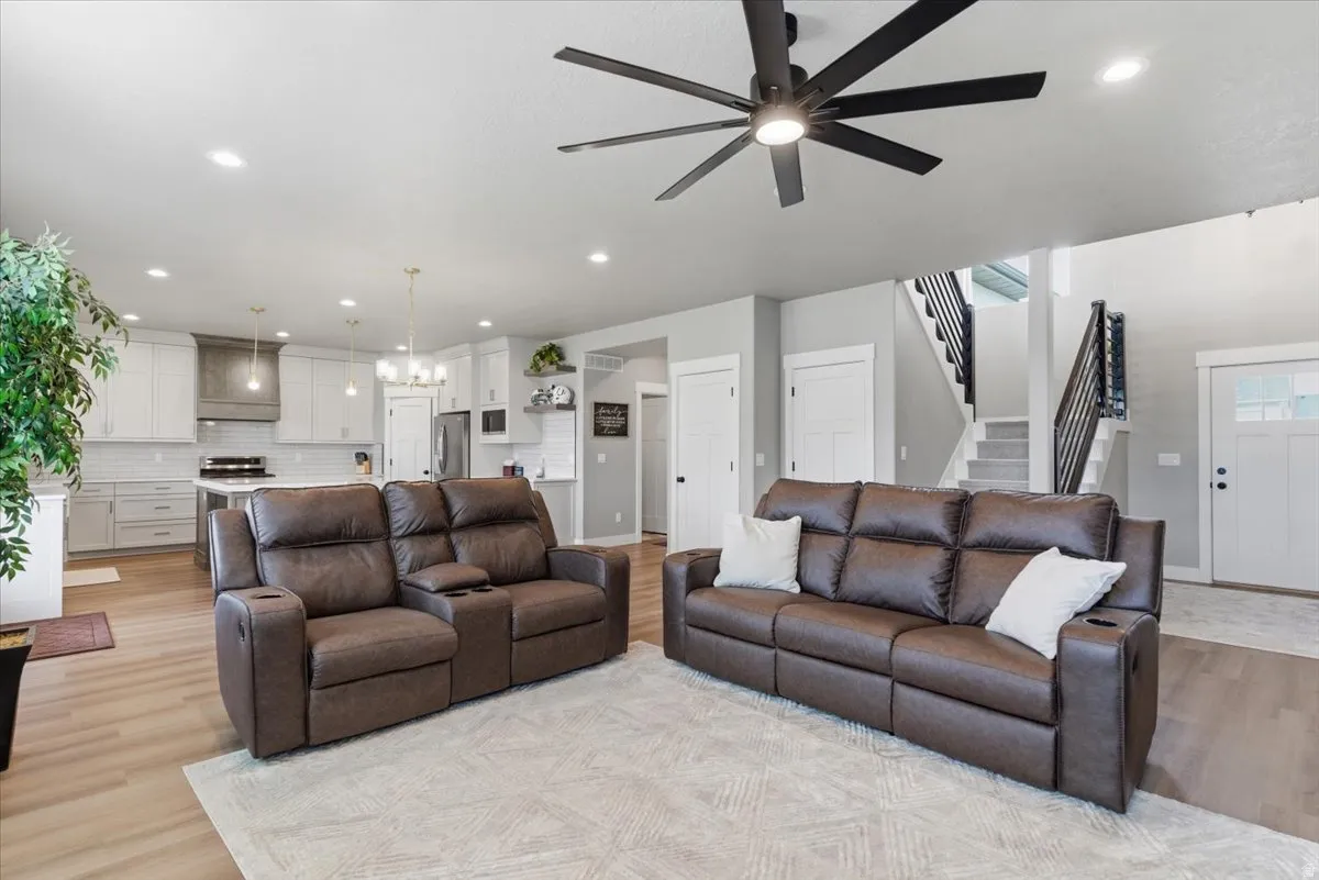 Living area with a ceiling fan, light wood-style floors, and a chandelier