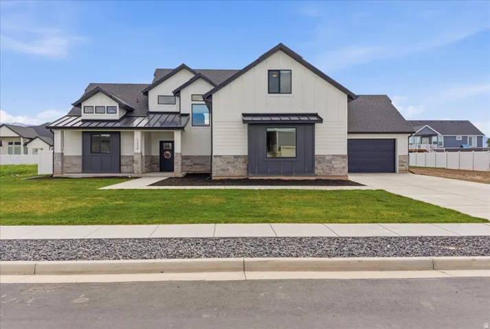 Modern farmhouse style home with stone siding, a standing seam roof, concrete driveway, an attached garage, and a porch