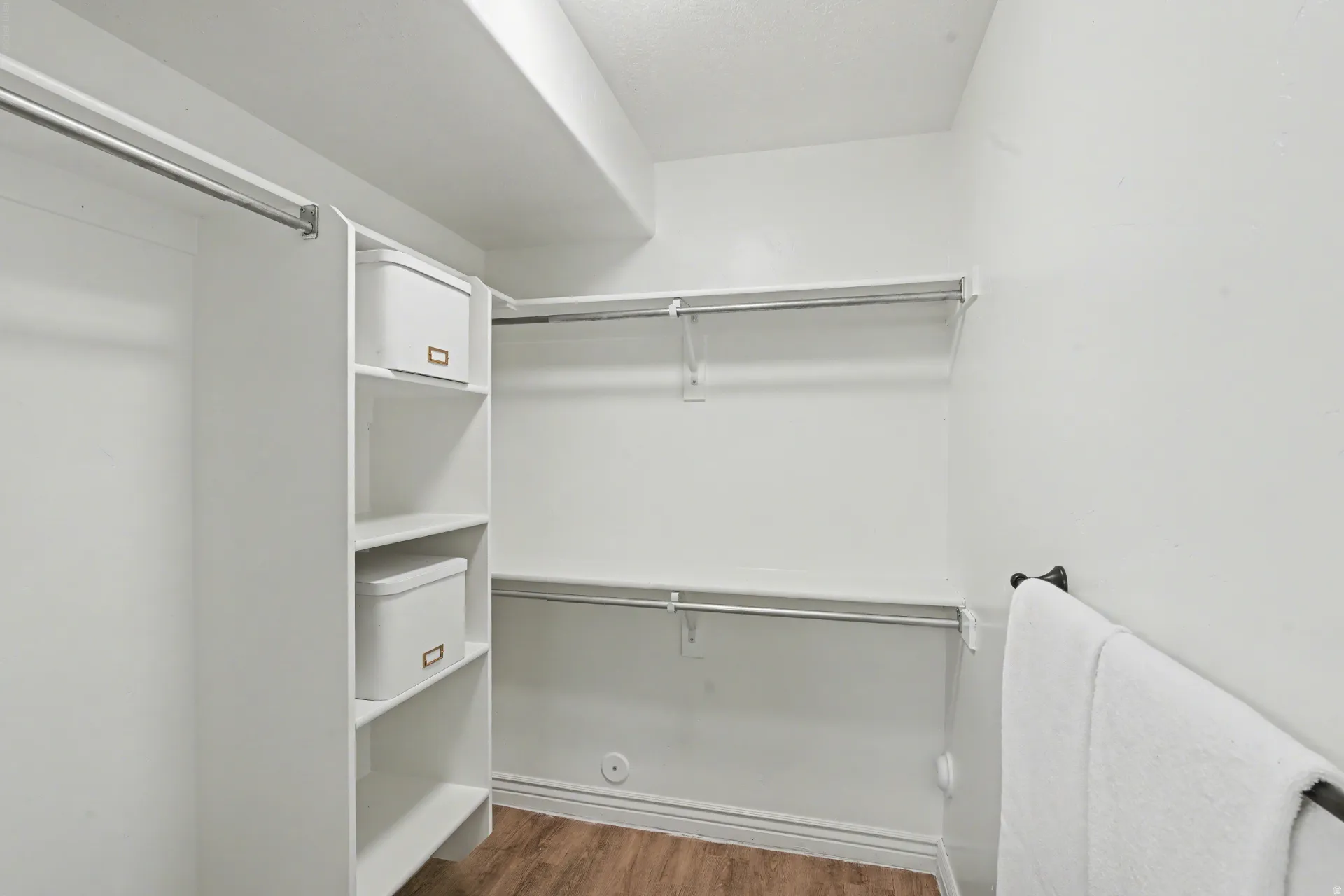 Walk in closet with dark wood-style flooring