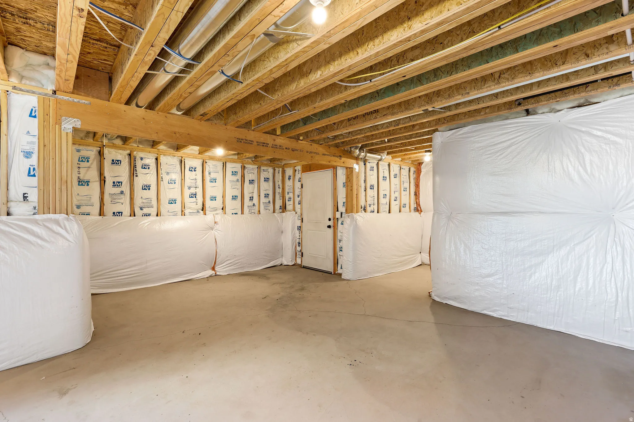 Unfinished basement with concrete flooring and exposed wood ceiling joists