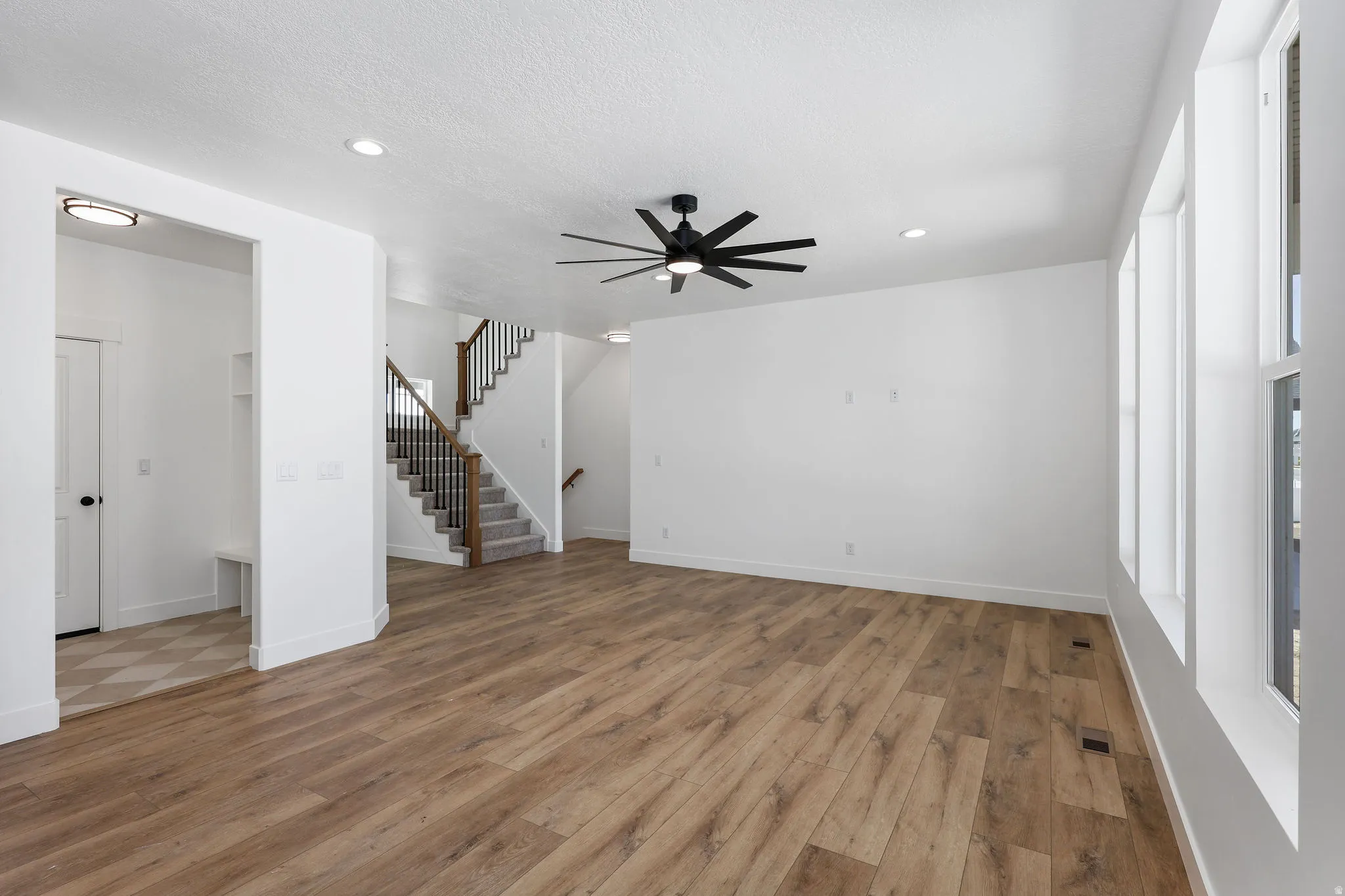 Spacious living area featuring wood-finish flooring, recessed lighting, and a contemporary ceiling fan