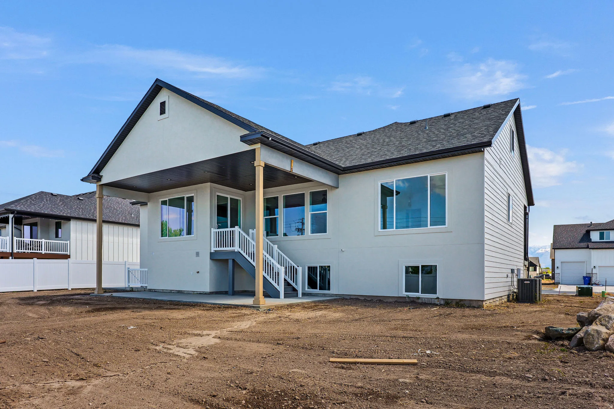 Rear exterior with a covered patio, composite deck stairs, and multiple large windows