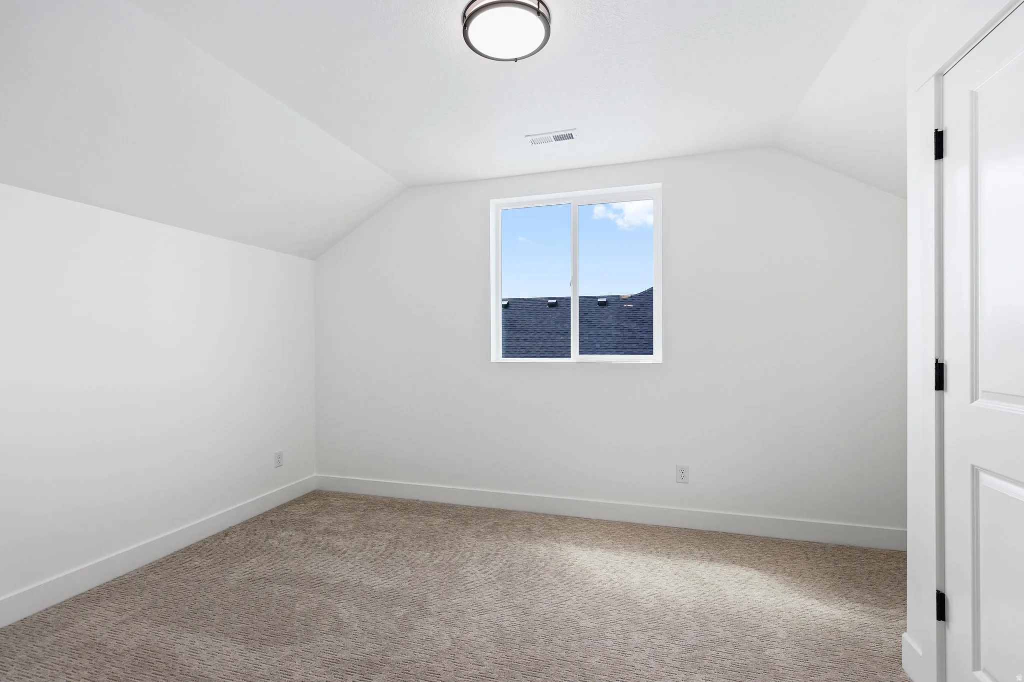 Bright interior space featuring a single pane window, white trim, and a low-pile carpet