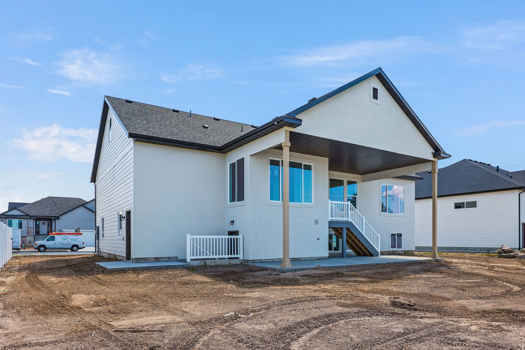 Rear exterior featuring a covered patio, multiple windows, and an exterior staircase with white railings