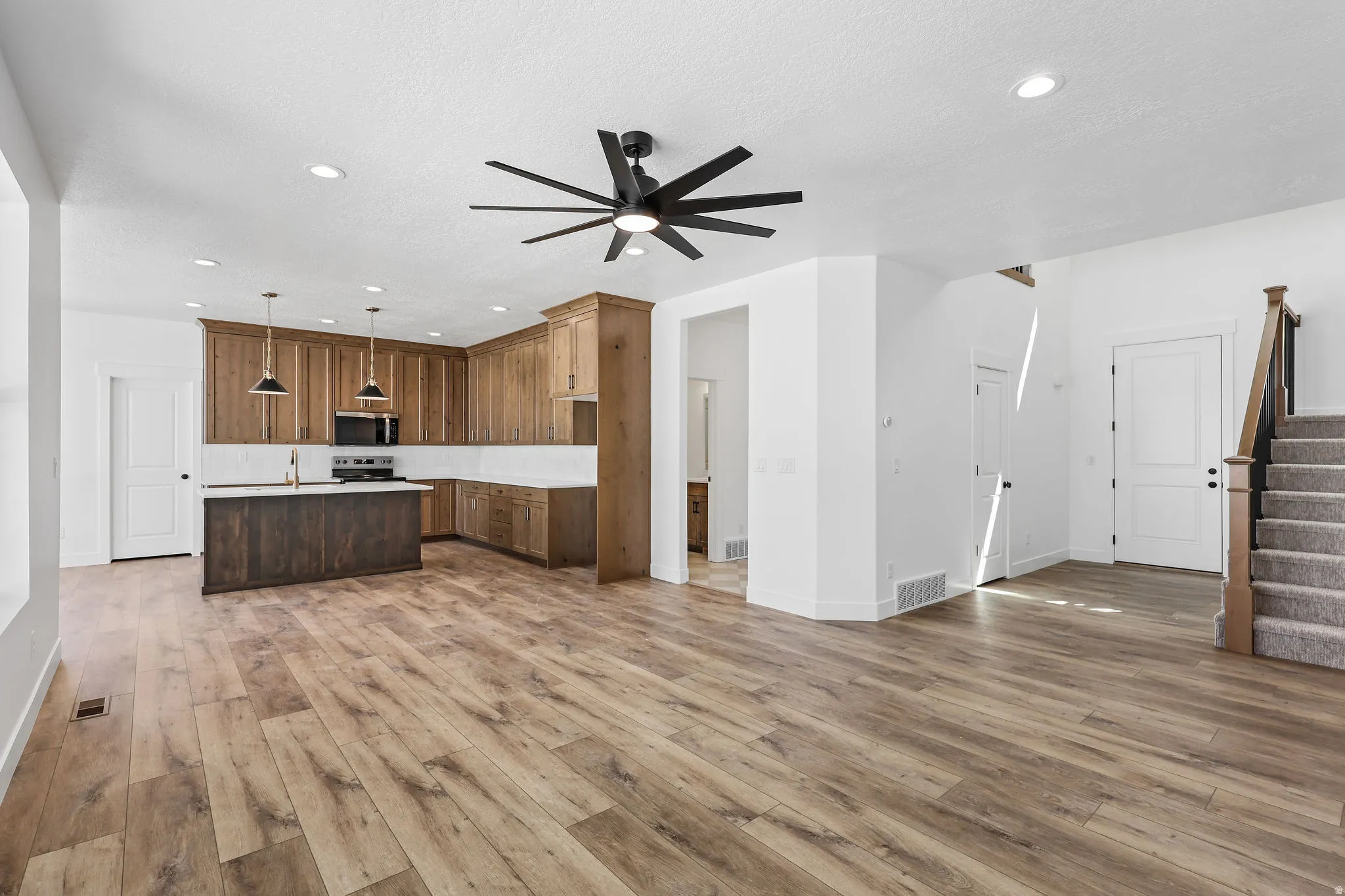 Open-concept living space with wood-finish flooring, a contemporary ceiling fan, and recessed lighting