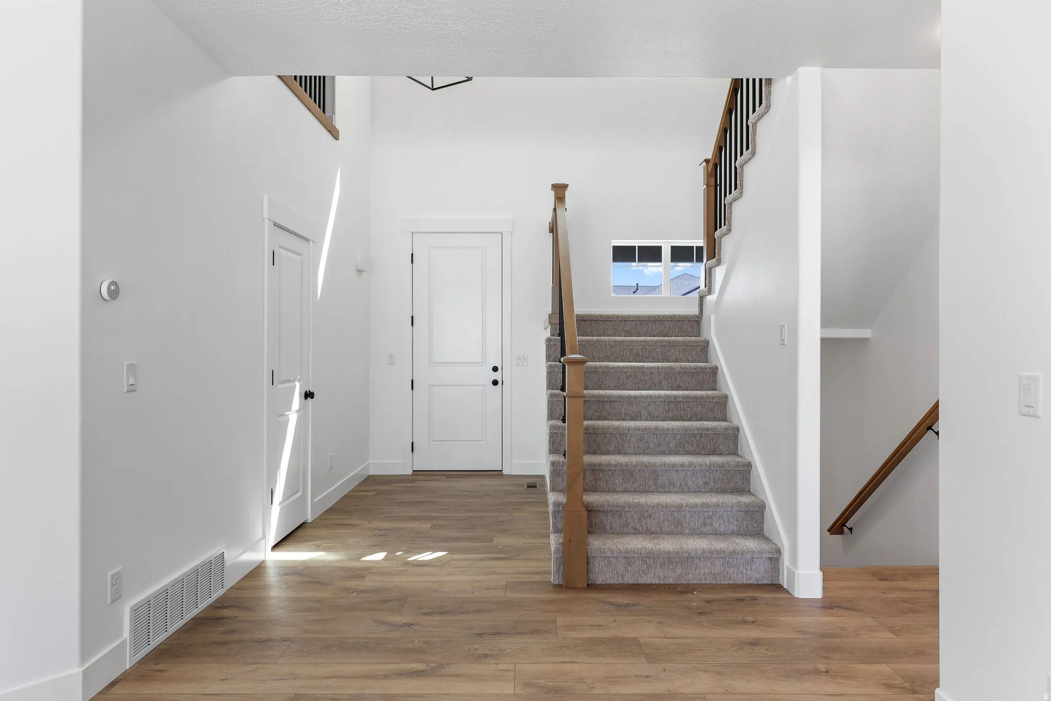 Entryway featuring wood-finish flooring and a carpeted staircase with wood and metal railings