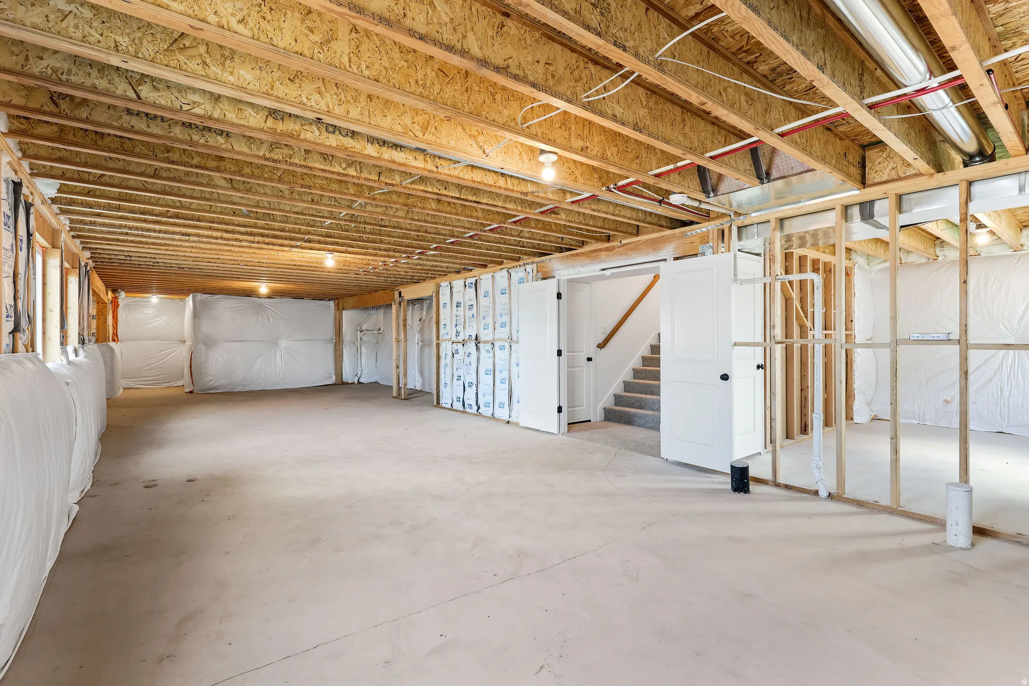 Unfinished basement with exposed ceiling joists and concrete flooring