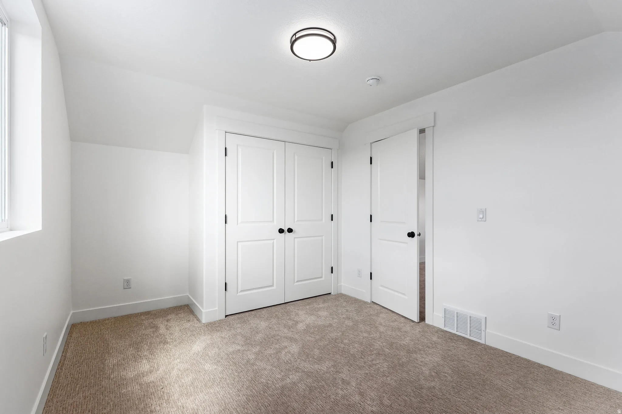 Bedroom featuring plush carpet flooring, white painted walls, a built-in closet with bifold doors, and a window for natural light