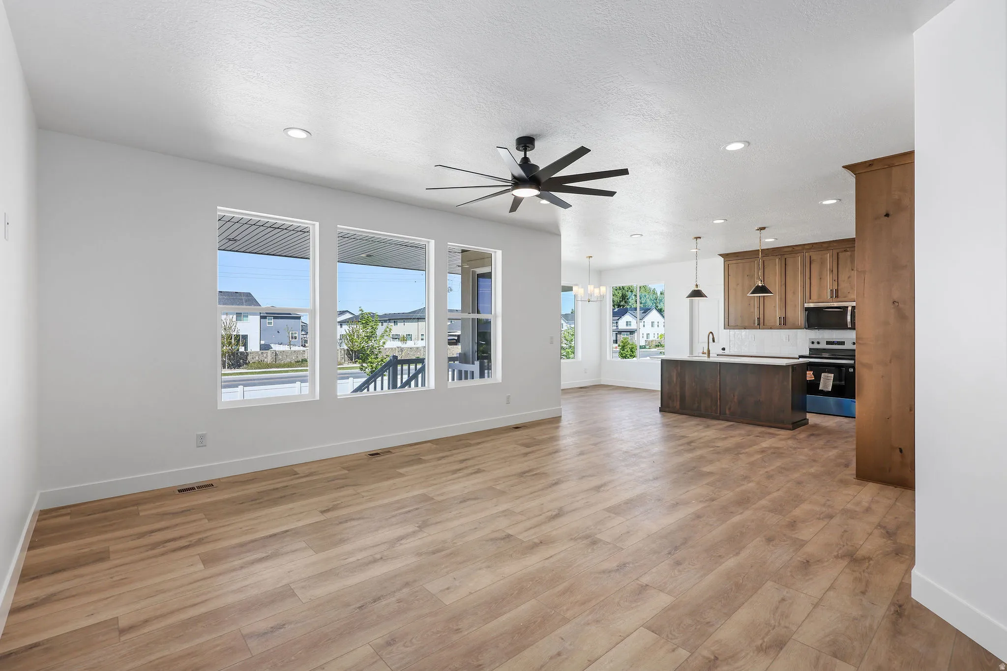 Open concept living space featuring wood-finish flooring, recessed lighting, and a dark-bladed ceiling fan