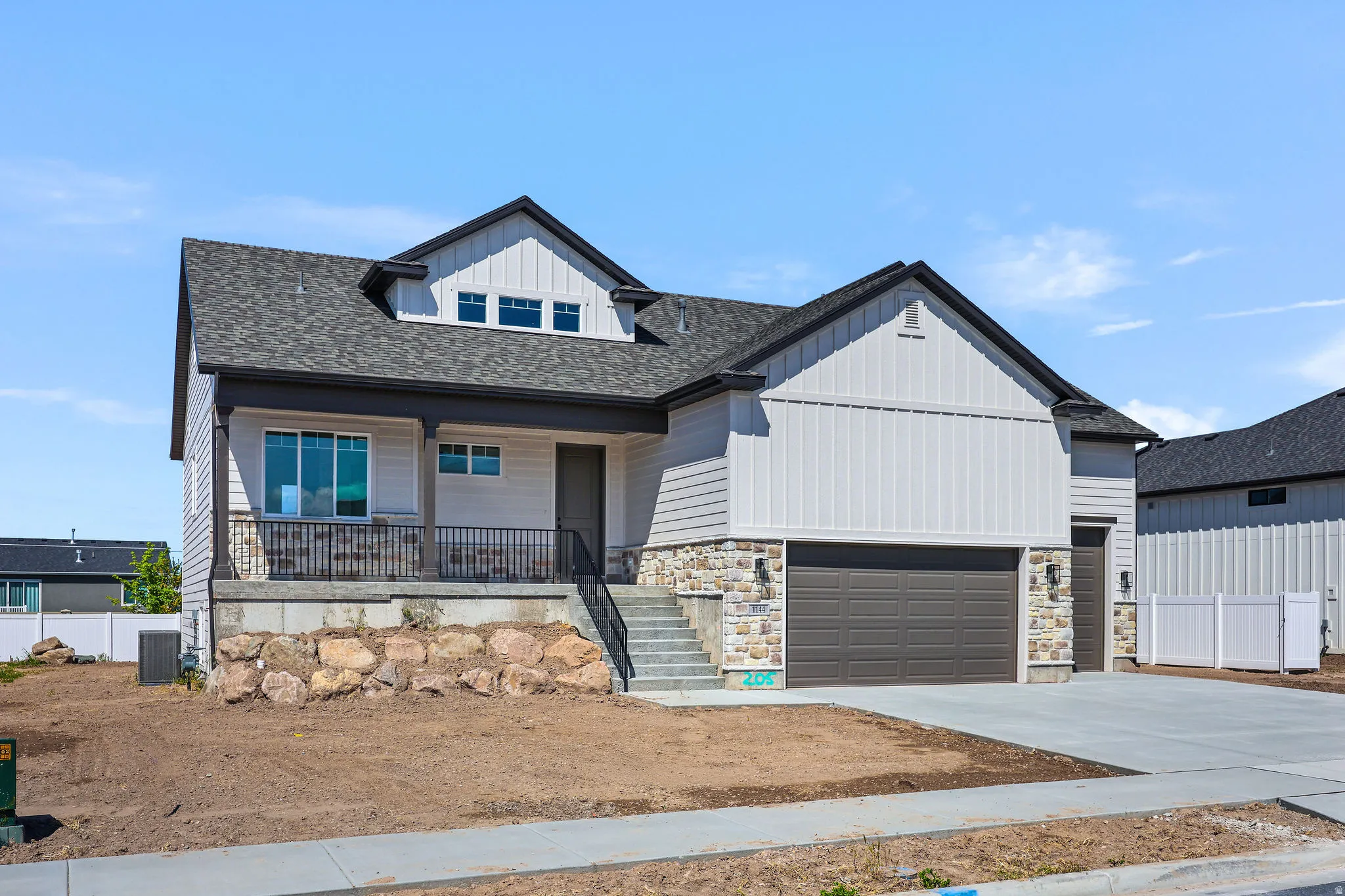 Modern two-story residence featuring light siding, stone accents, and a dark shingle roof