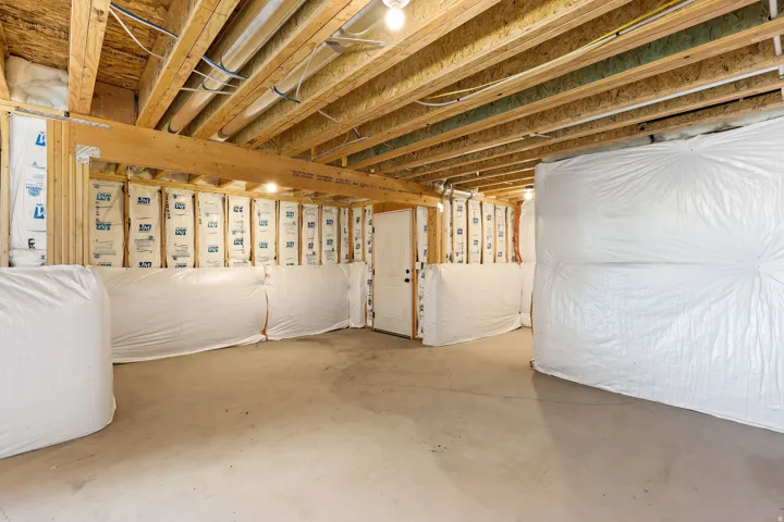 Unfinished basement with concrete flooring and exposed wood ceiling joists