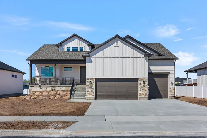 Modern Farmhouse exterior featuring a covered front porch, a two-car garage, stone accents, and vertical siding