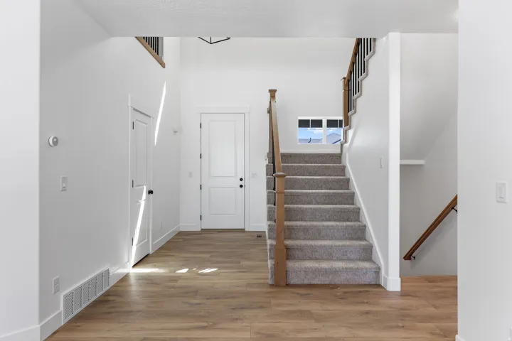 Entryway featuring wood-finish flooring and a carpeted staircase with wood and metal railings