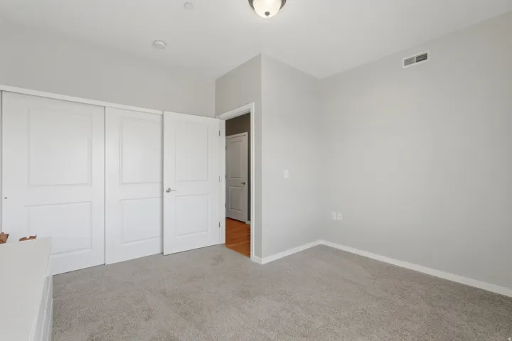 Unfurnished bedroom with light carpet and a closet