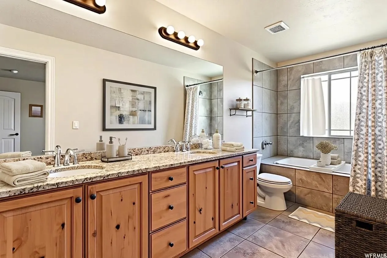 Spacious bathroom featuring a double vanity with granite countertops, dual undermount sinks, and wood cabinetry