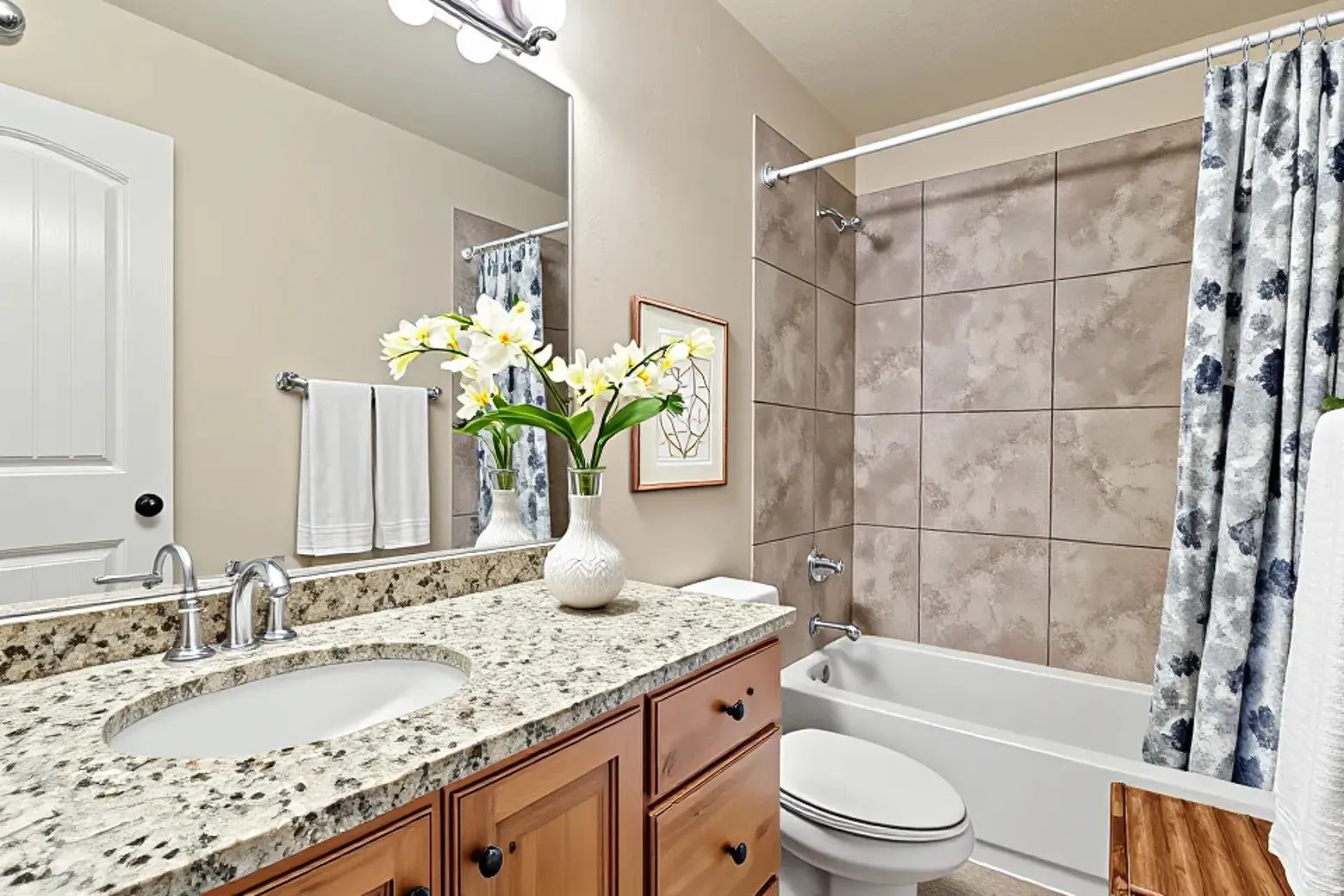 Bathroom featuring a wood-finish vanity with a granite countertop, undermount sink, and chrome faucet