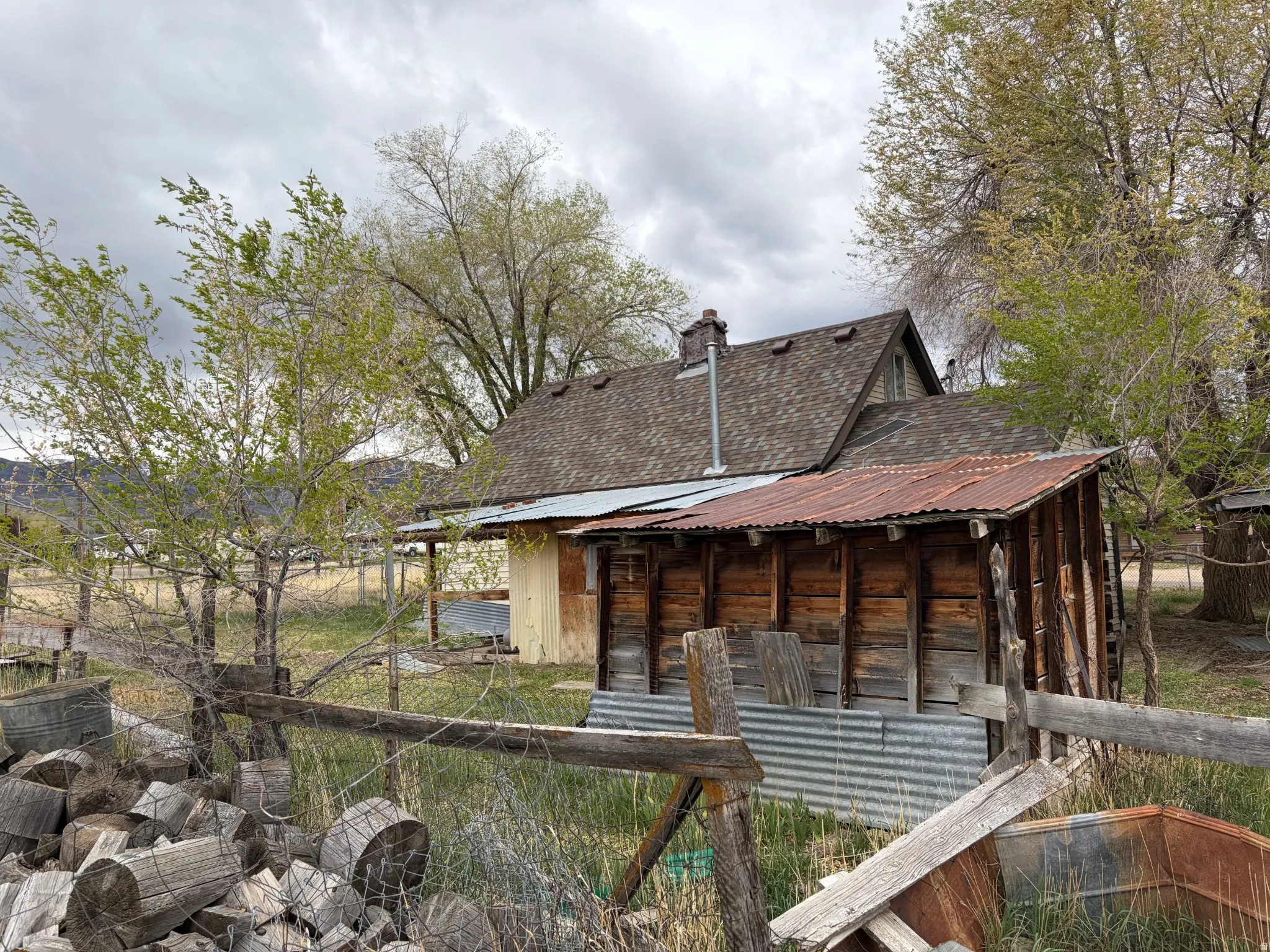 Rear view of property with a chimney, an outbuilding, a metal roof, and a shingled roof