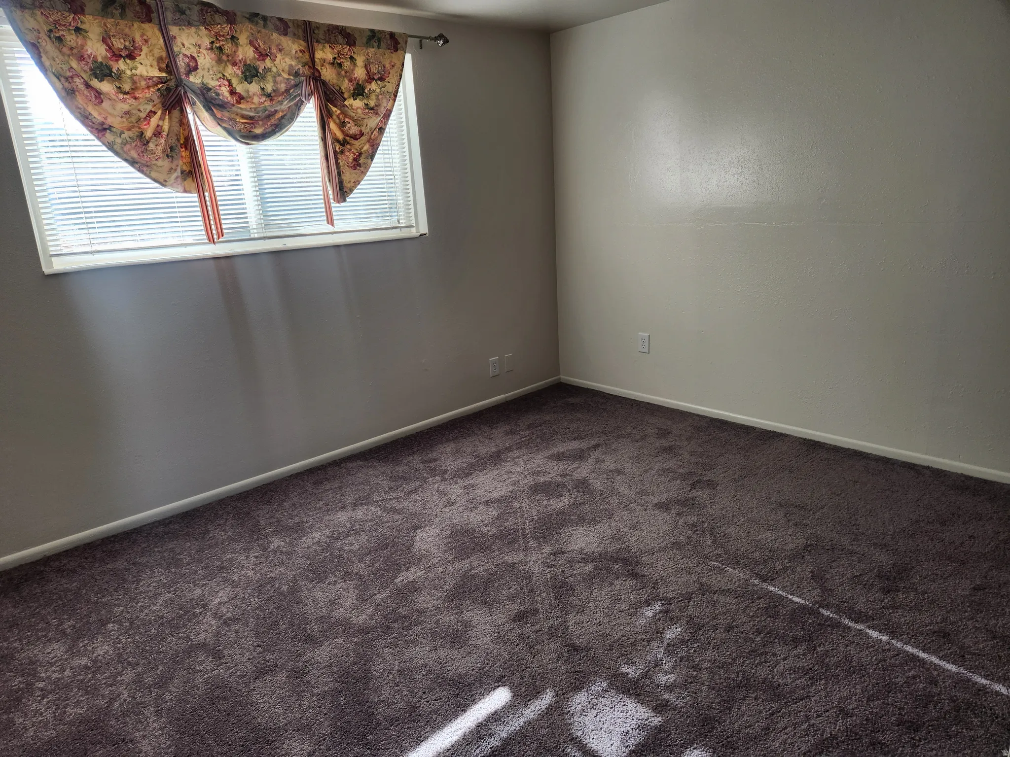 Spare room featuring baseboards and dark colored carpet