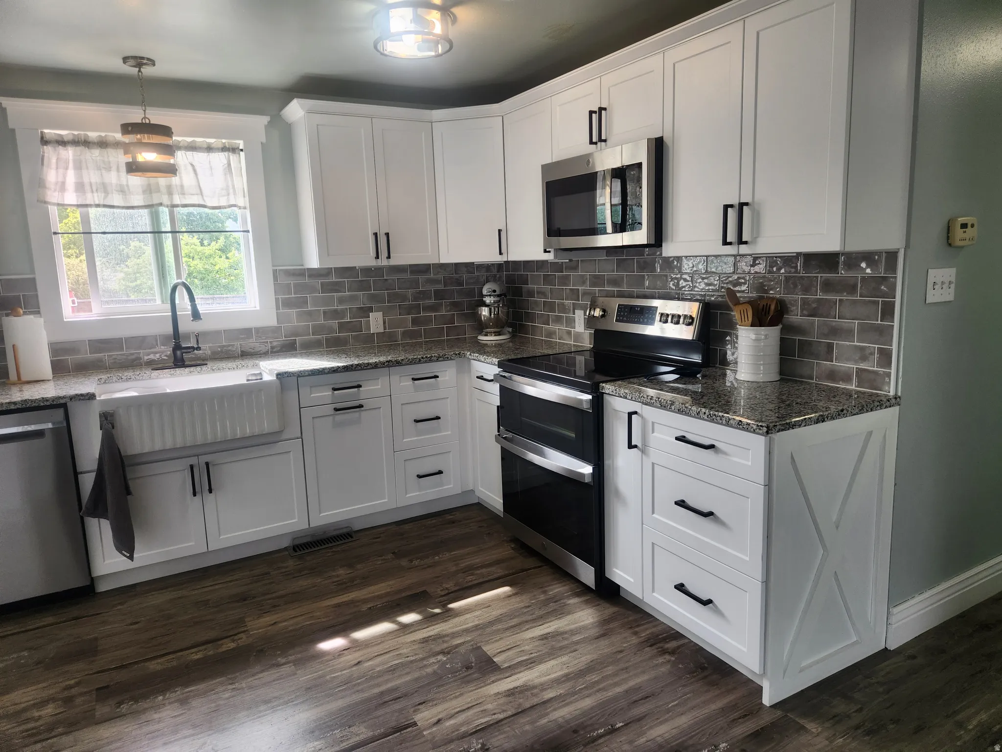 Kitchen with stainless steel appliances, dark stone countertops, and white cabinetry