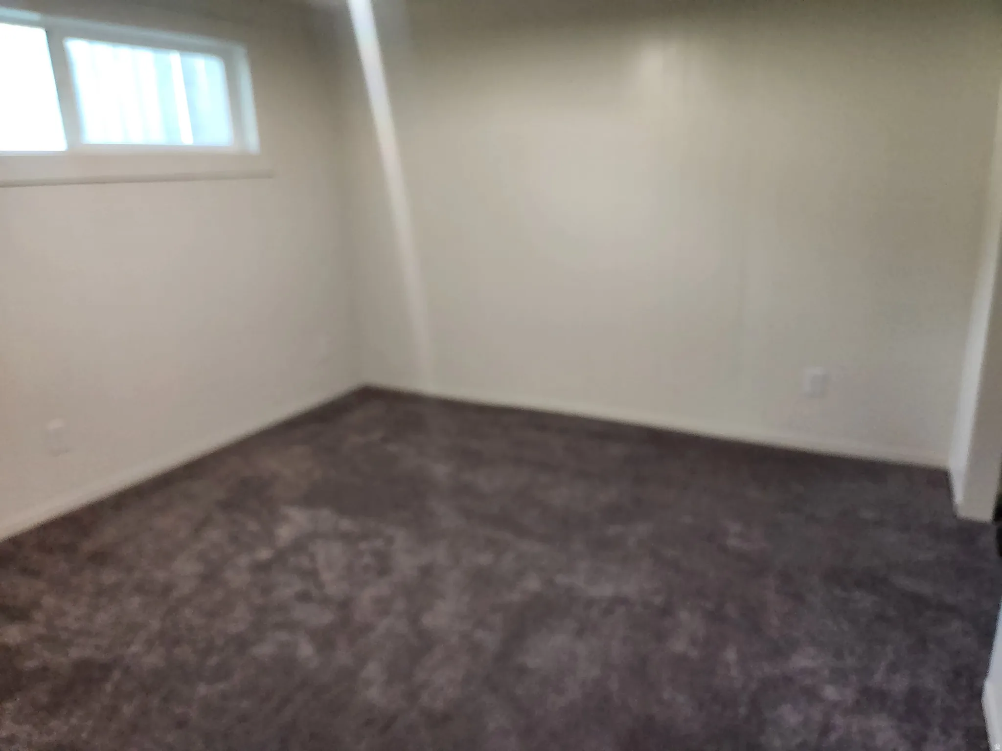 Basement with dark colored carpet and baseboards