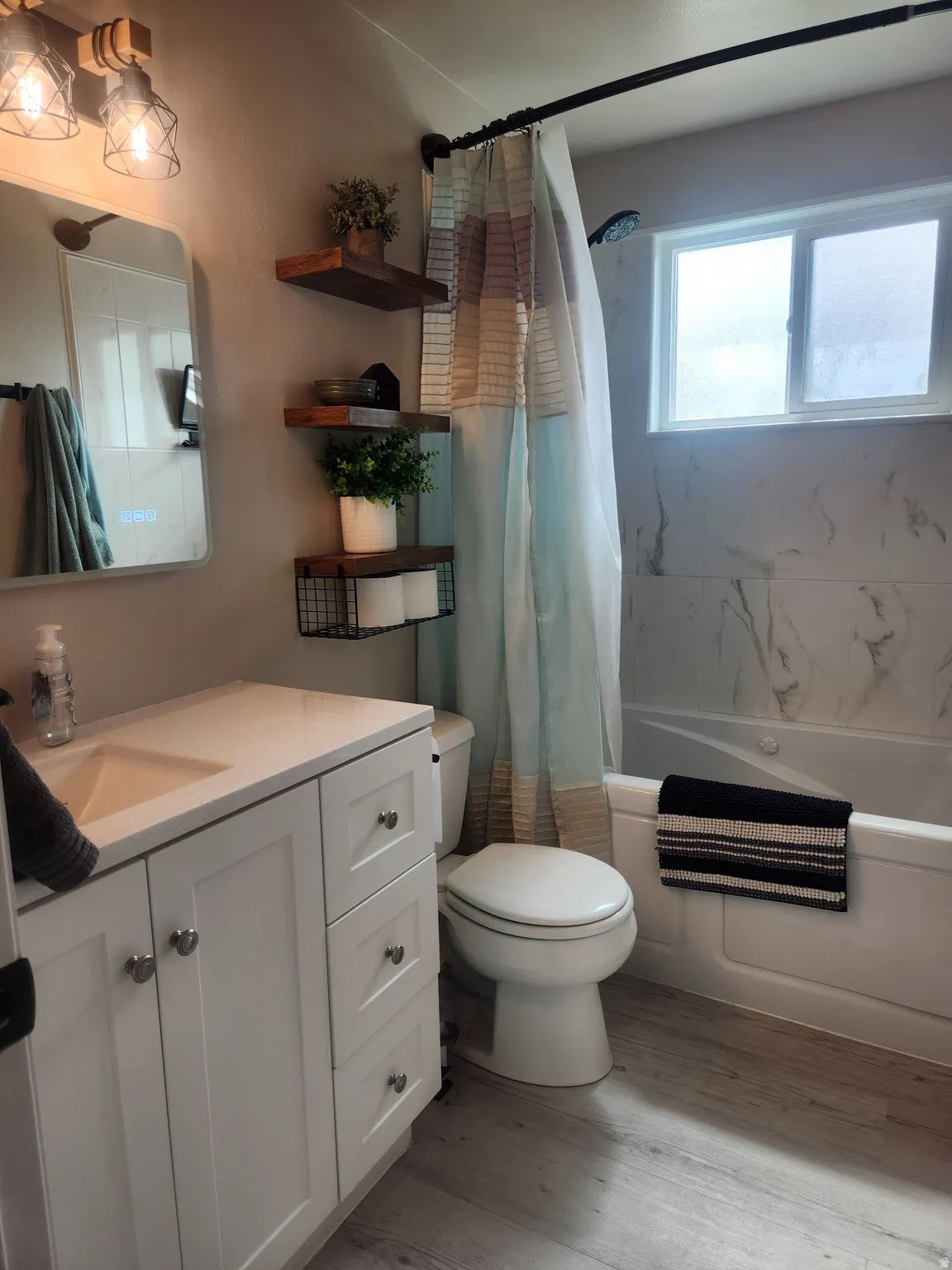 Full bath featuring vanity, light wood-style flooring, and shower / tub combo with curtain