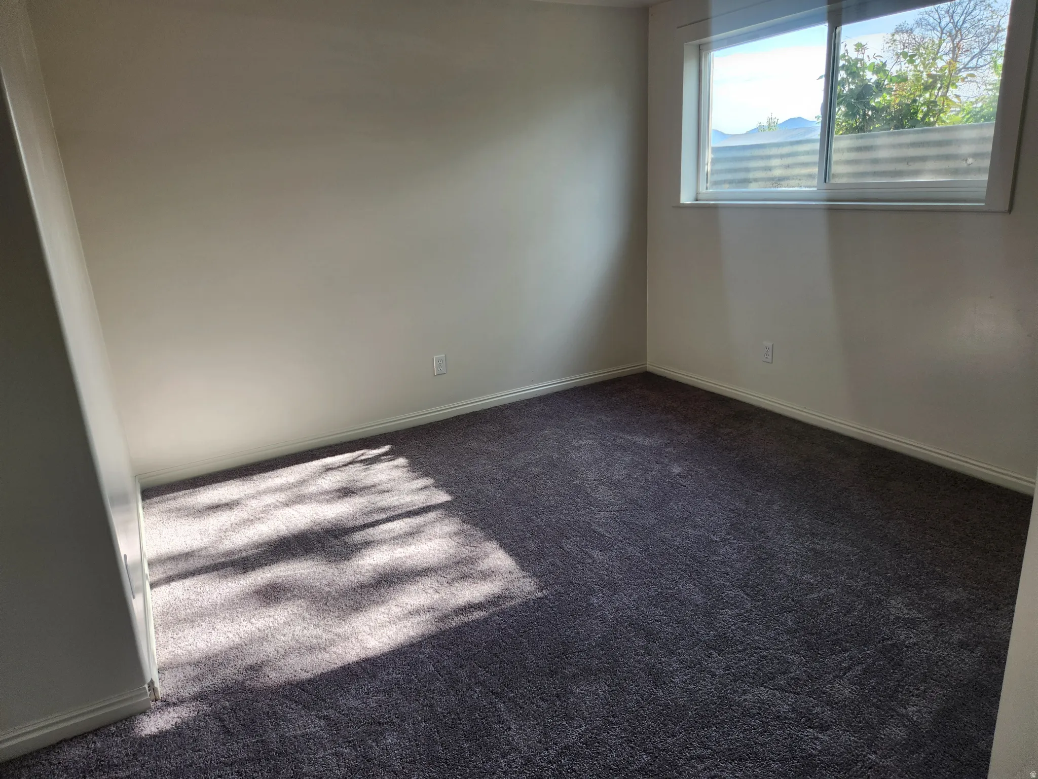 Carpeted spare room featuring baseboards
