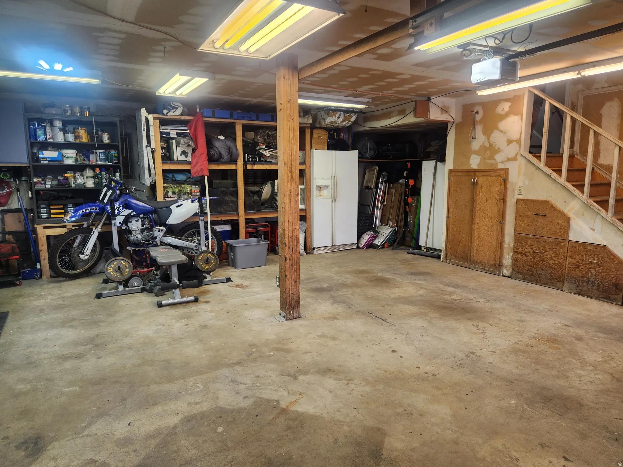 Basement with white refrigerator with ice dispenser and stairs