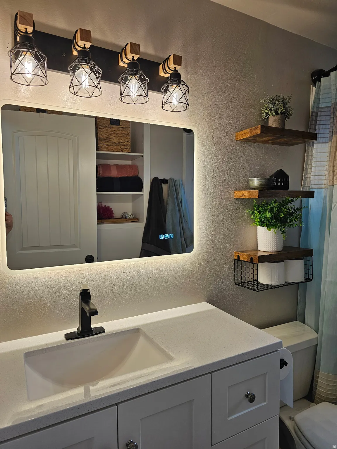 Bathroom with a textured wall, vanity, and a shower with curtain