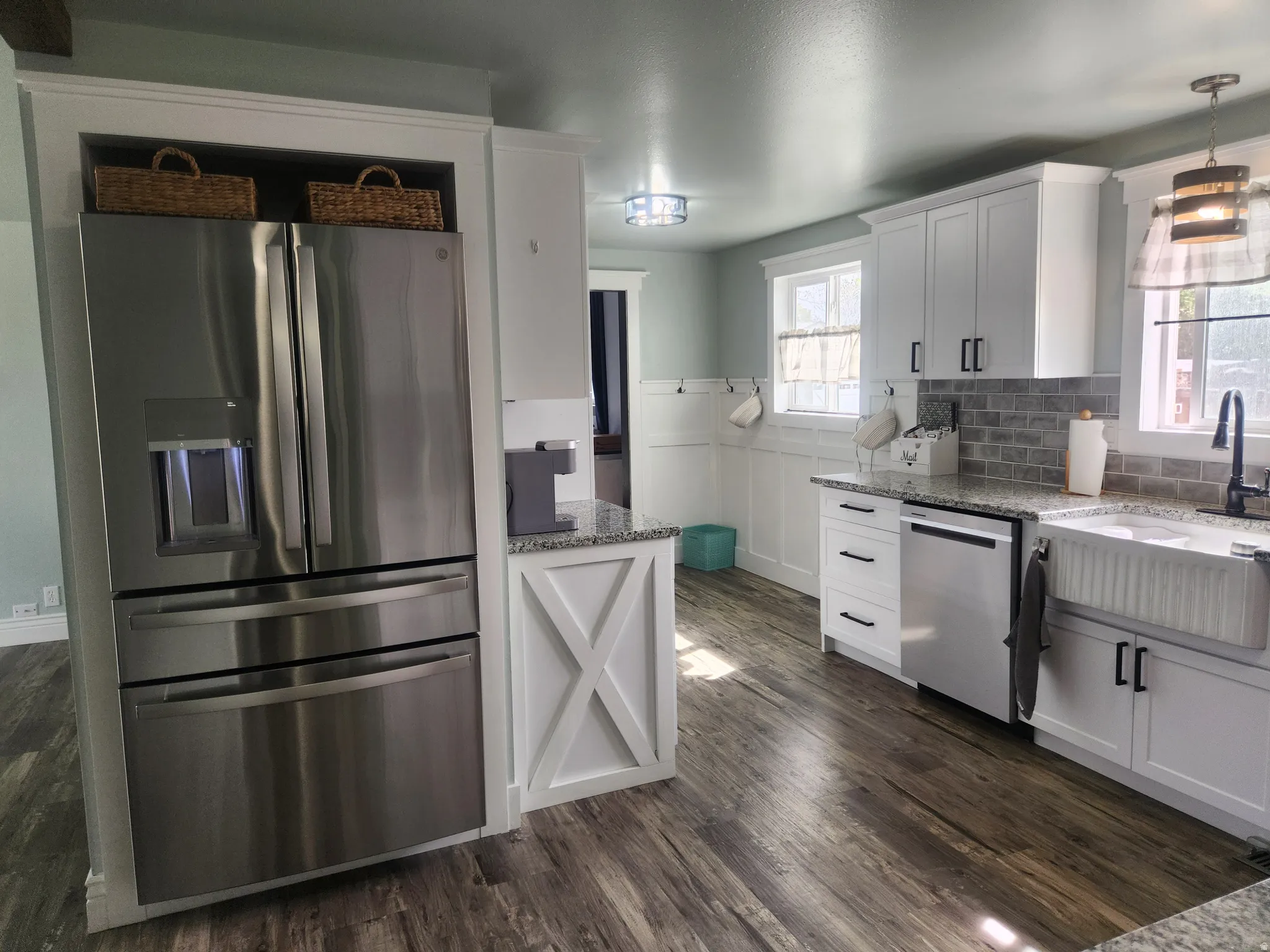 Kitchen featuring stainless steel appliances, light stone countertops, white cabinets, and dark wood-style flooring