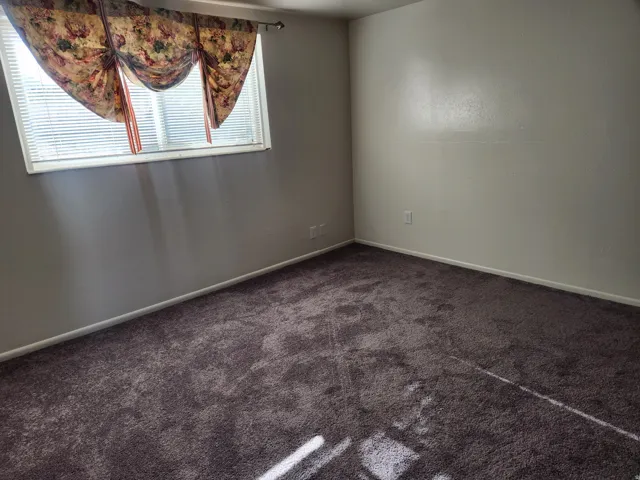 Spare room featuring baseboards and dark colored carpet
