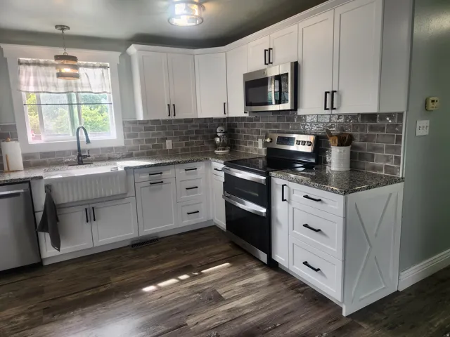 Kitchen with stainless steel appliances, dark stone countertops, and white cabinetry