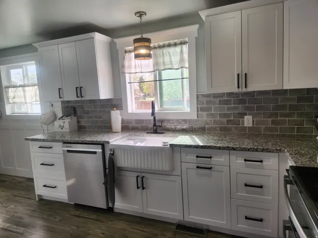Kitchen with stainless steel appliances, light stone countertops, and white cabinets