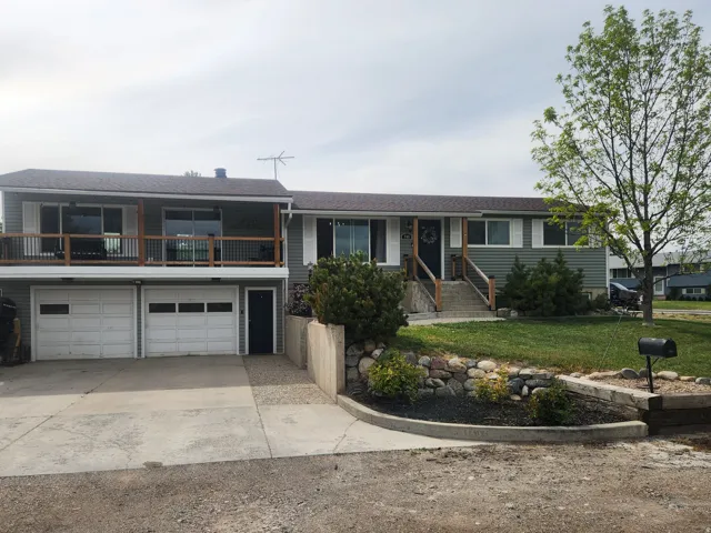 View of front of property with concrete driveway, an attached garage, a front lawn, a balcony, and a shingled roof