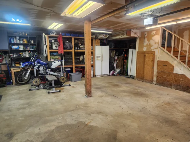 Basement with white refrigerator with ice dispenser and stairs