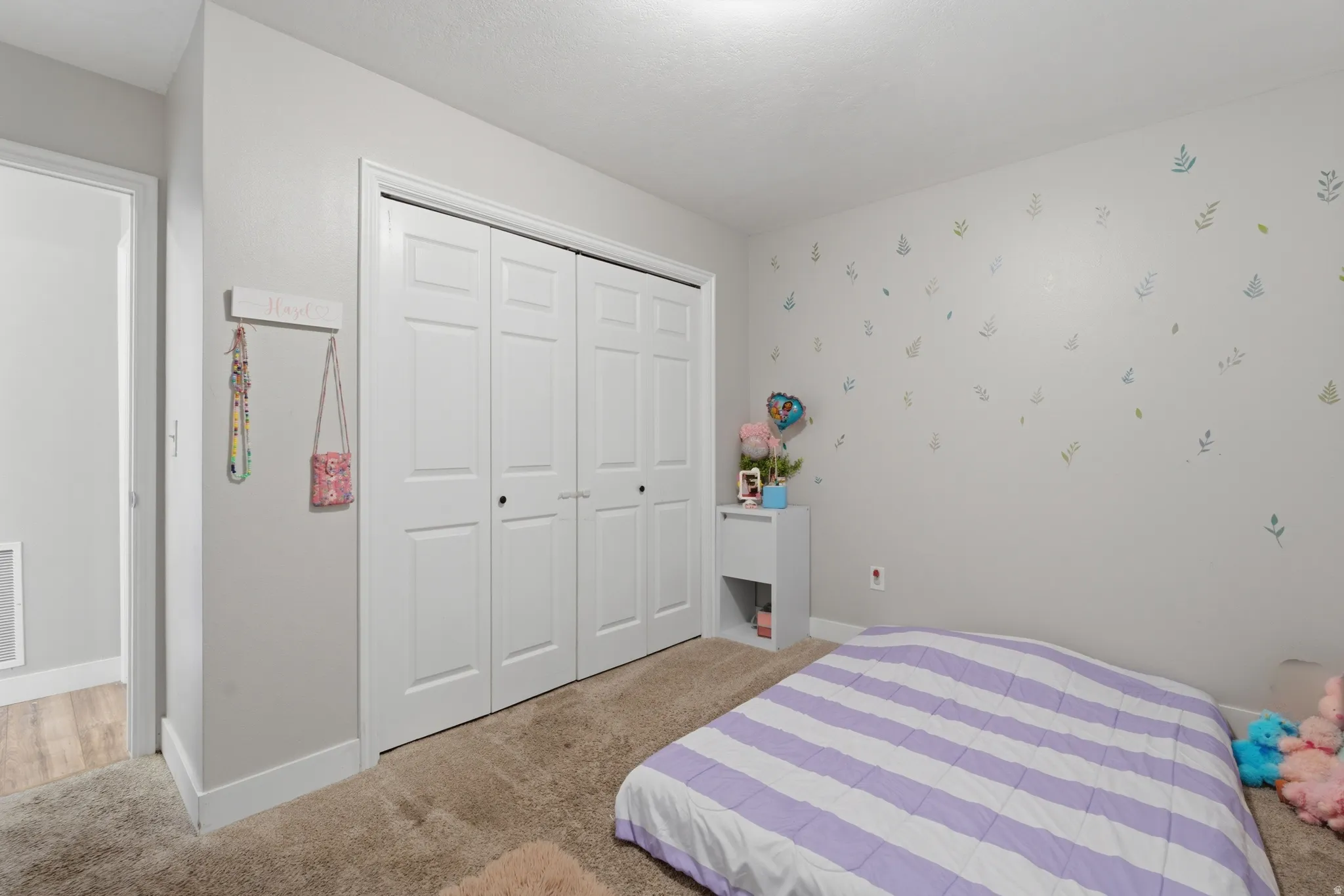 Bedroom with light colored carpet and a closet